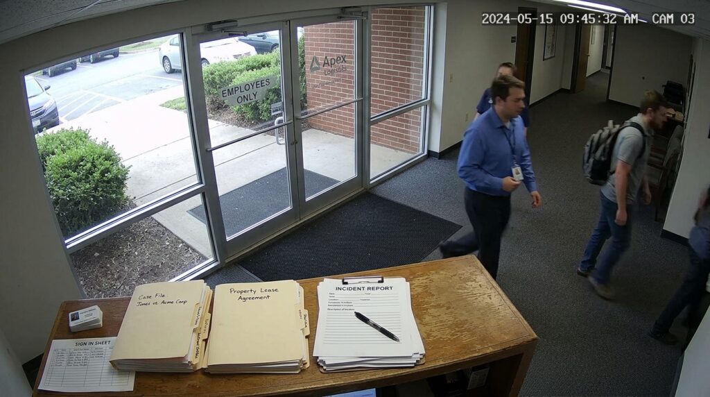 A wide-angle security camera view of an office building entrance lobby showing individuals walking past a reception desk containing an incident report, a property lease agreement, and case files.